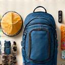 A neatly organized backpack with essential hiking gear laid out, including boots, water bottle, hat, and emergency kit, representing packing essentials.